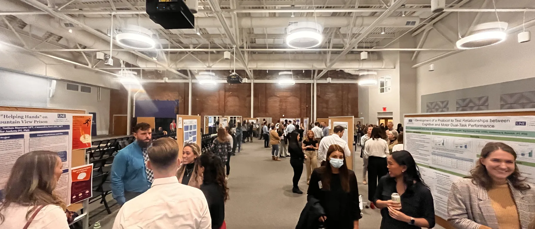 Physical therapy students present at their annual research symposium. Crowds gather to watch presentations