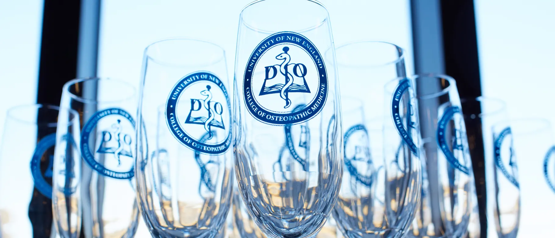 Champagne flutes branded with the UNE COM logo are arranged on a table