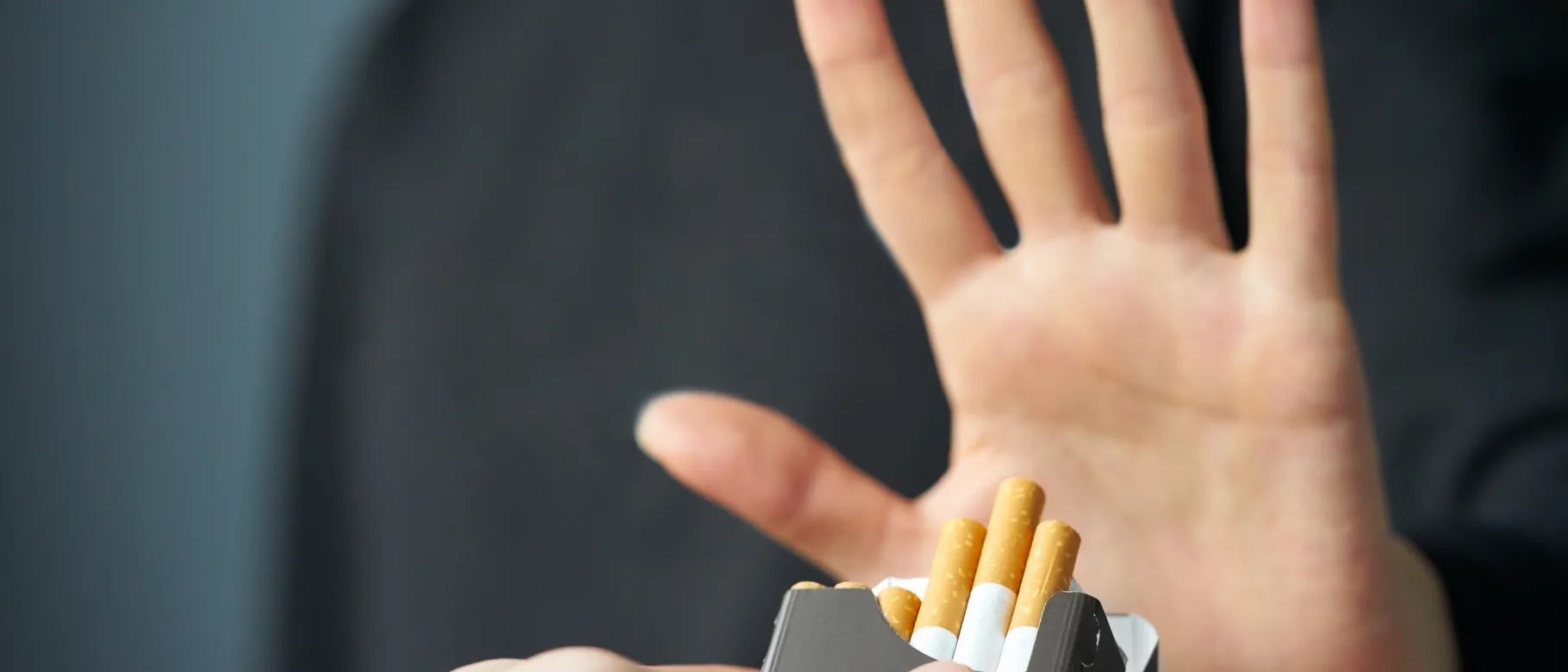 Stock image of a person raising their hand "no" to an offer for a cigarette