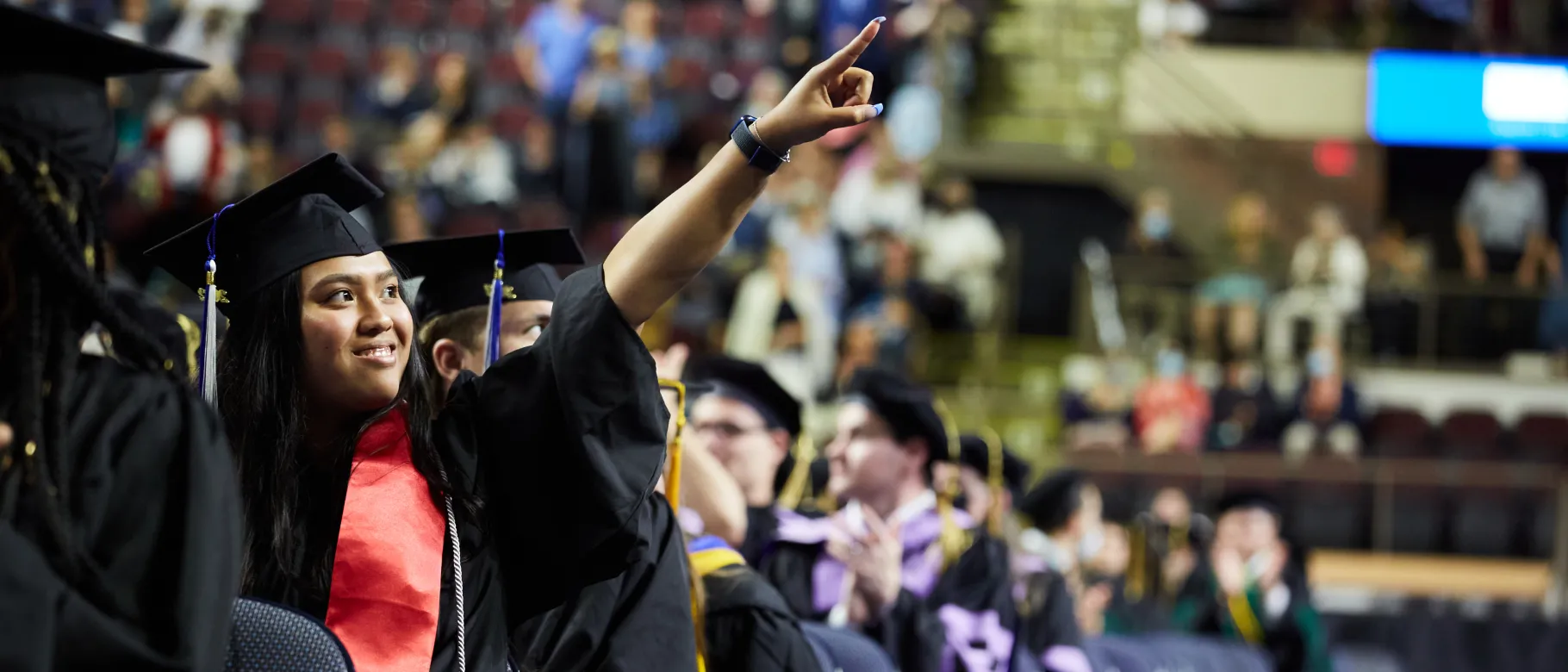 A student points to the crowd during the 187th Commencement ceremony at the Cross Insurance Arena in Portland