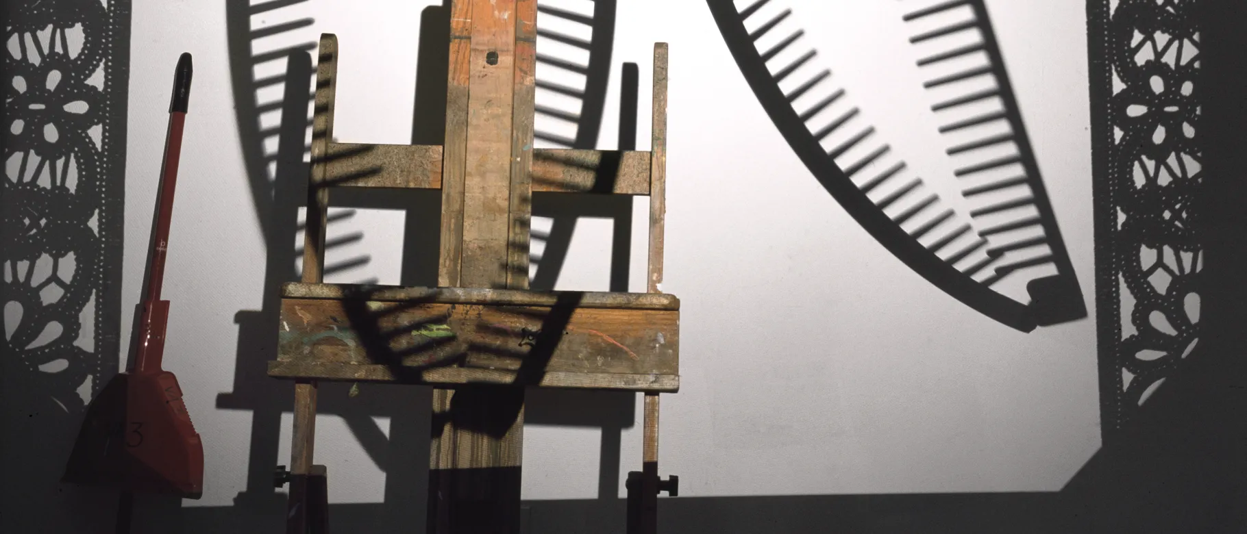 A photo of a broom and an easel with black shadows behind it