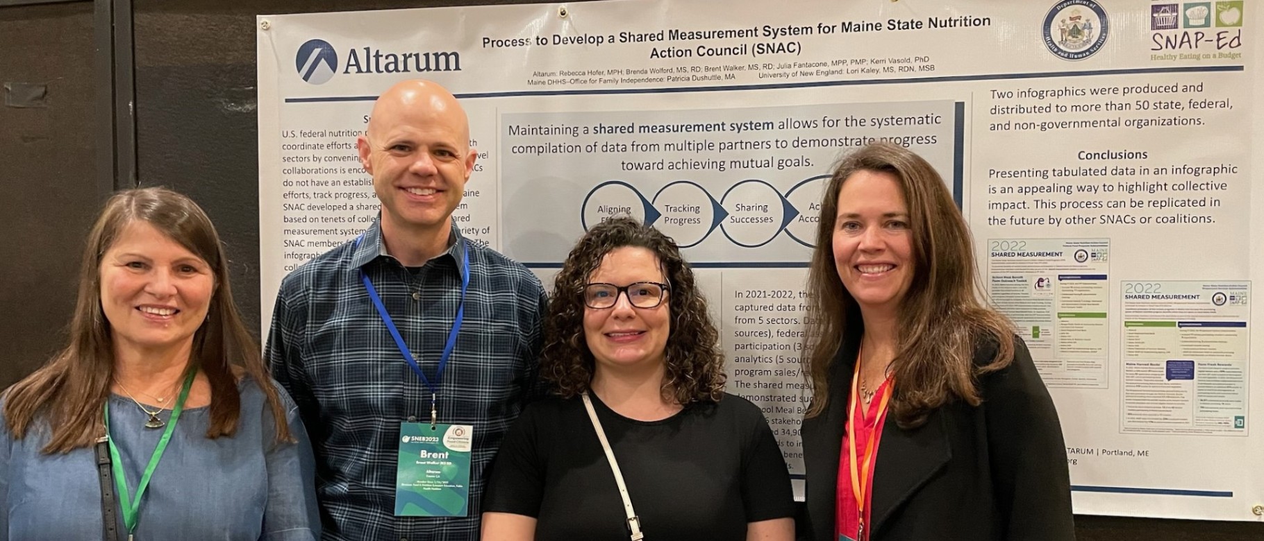 Four researchers pose in front of a poster at a conference. Lori Kaley (UNE) is far left.