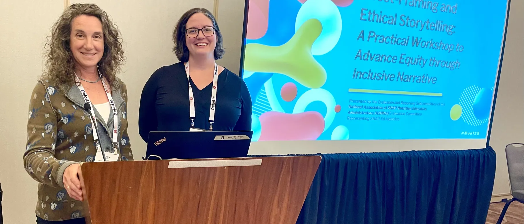 Pamela Bruno (left) and Colleen Fuller from UNE's Center from Excellence in Public Health pose for a photo next to a slideshow presentation displayed on a screen
