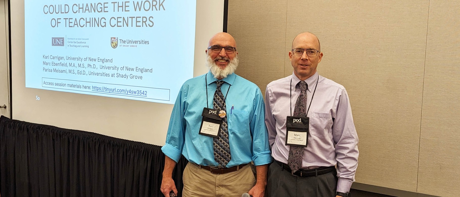 CETL's Karl Carrigan and Marc Ebenfield pose in front of a slideshow presentation at a conference