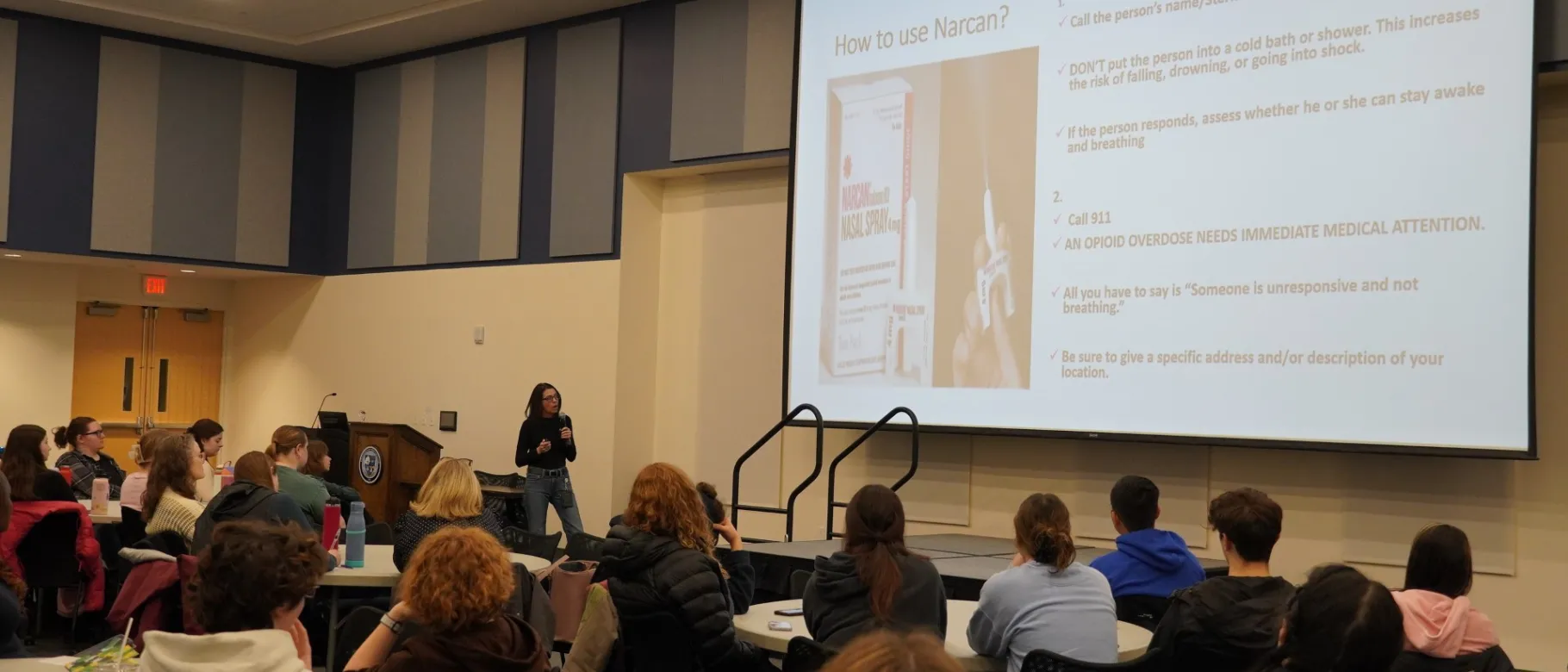 A woman presents a slide deck to a room of students