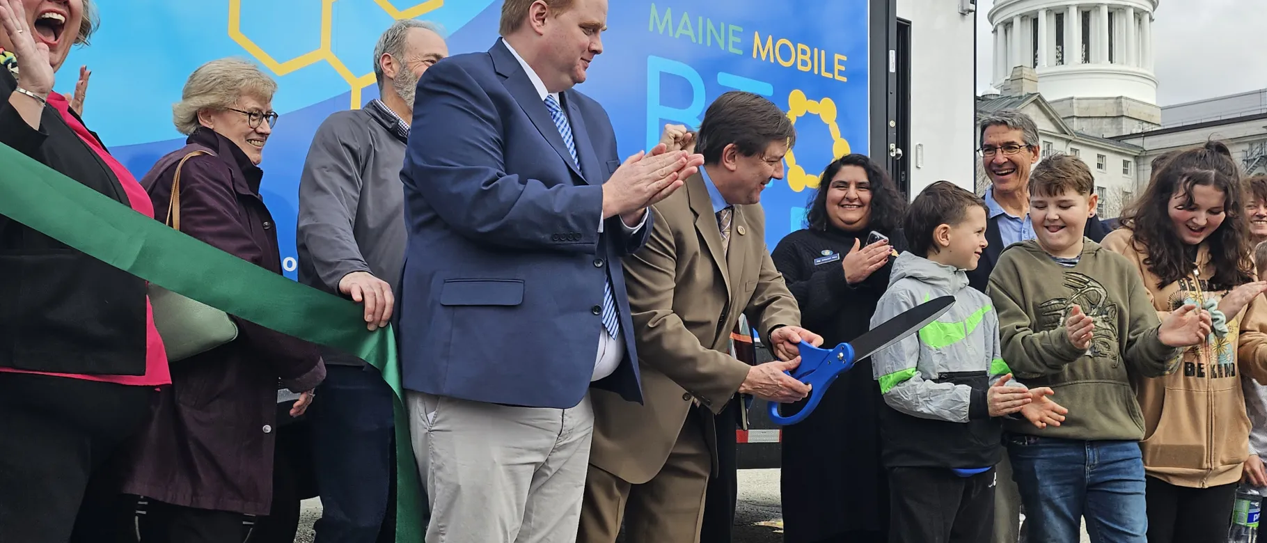 A crowd cheers at a ribbon cutting ceremony 