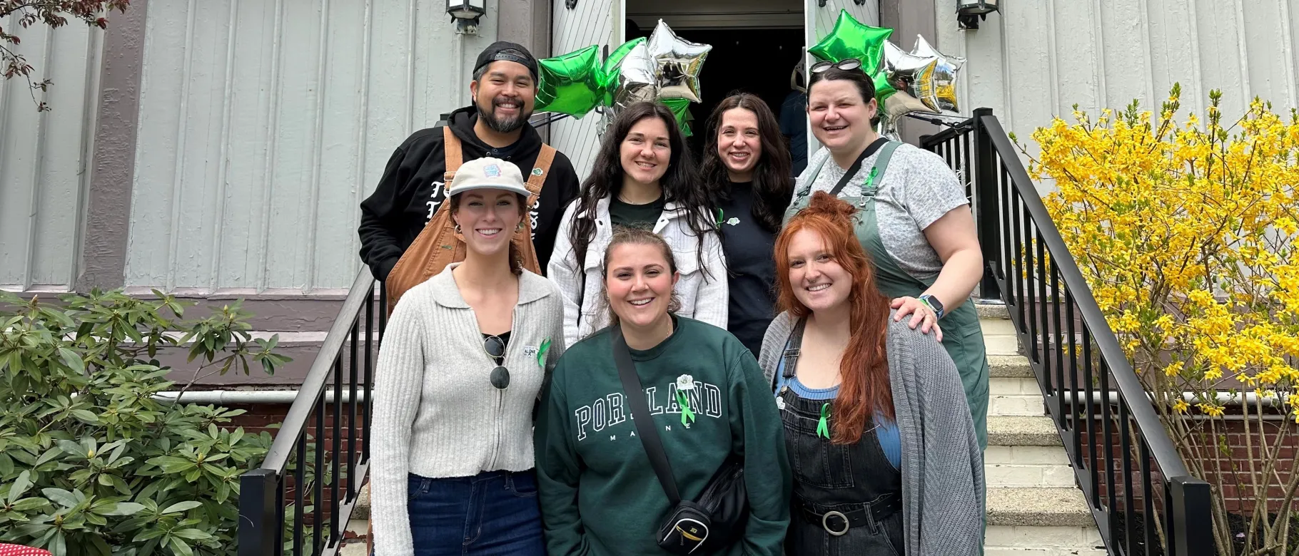A group of UNE students poses in front of UNE's Ludcke Auditorium 