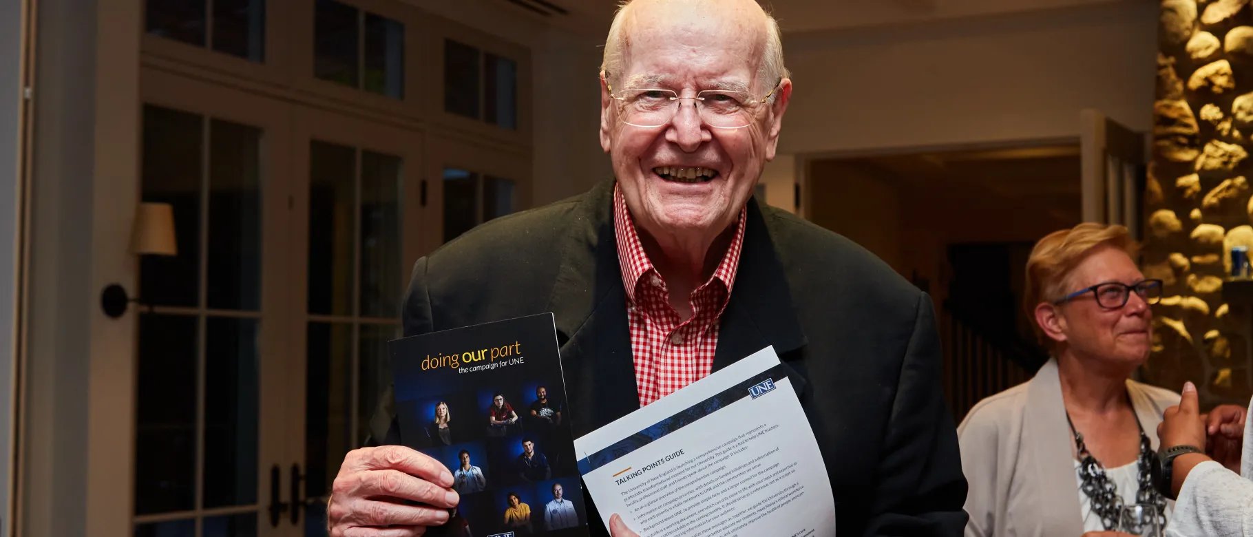 A photo of Robert McAfee holding a "Doing Our Part" brochure and smiling