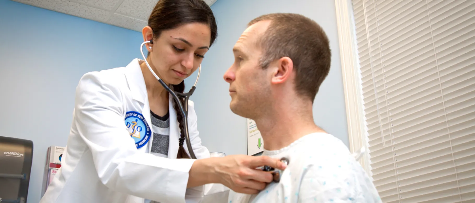 A UNE medical student listens to the heartbeat of an older adult during a health screening