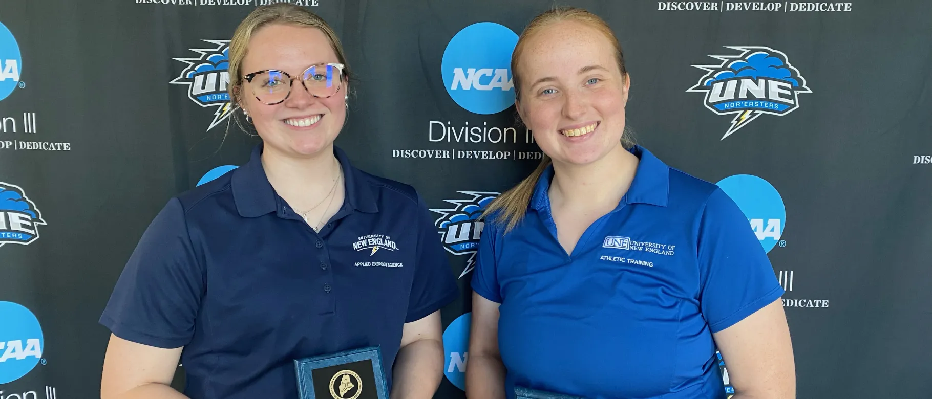 Two female students pose for a photo holding awards