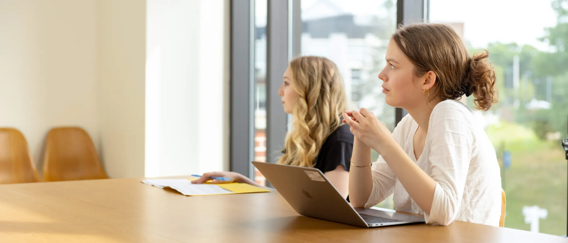 Students listen in a classroom while working on a laptop
