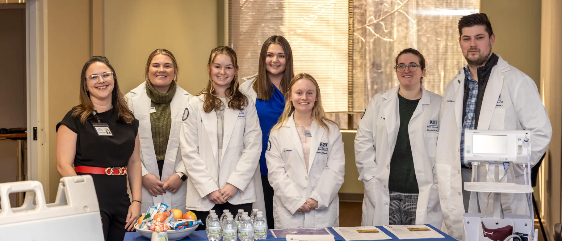 Pharmacy students pose with a UNE alum at a blood pressure clinic
