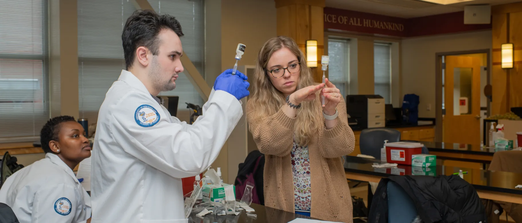 UNE pharmacy students draw vaccines from vials in a lab setting