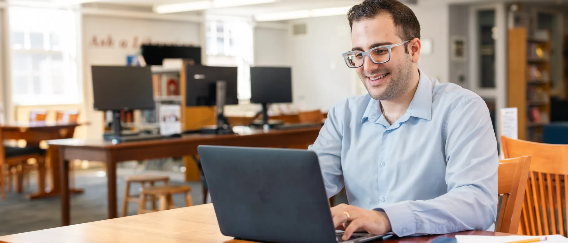 A UNE student works at his laptop in the Portland Campus library