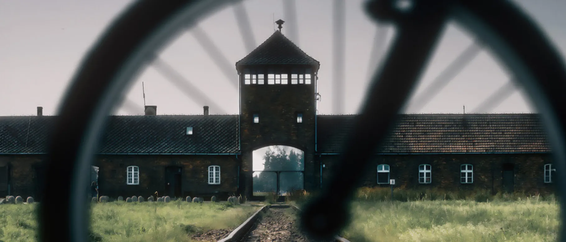 A view of the entrance to Auschwitz-Birkenau as seen through the spokes of a bike wheel