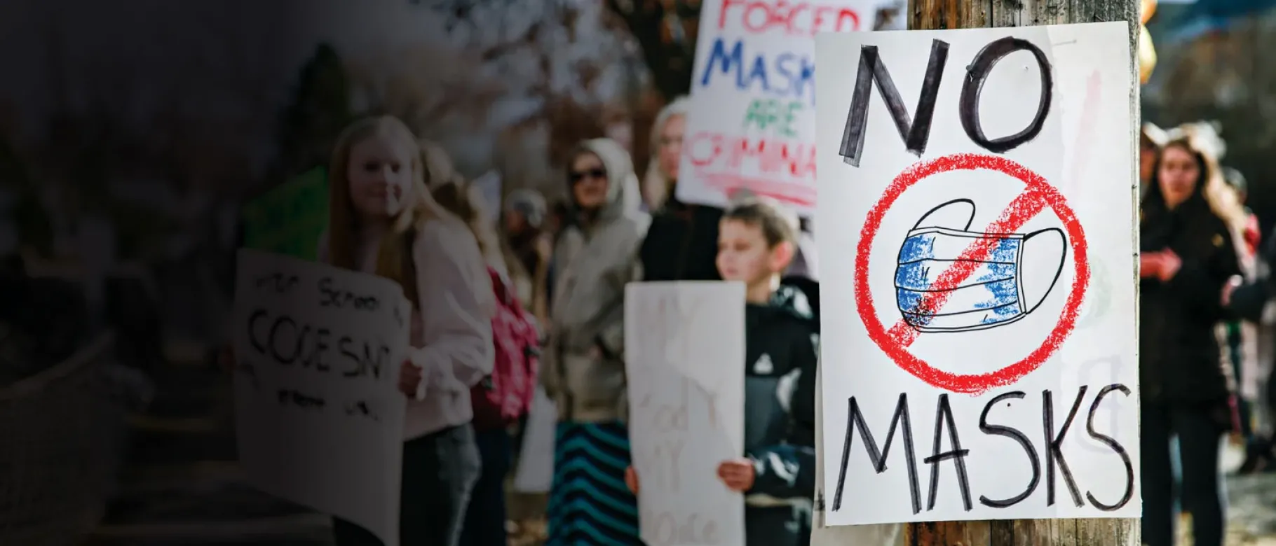 A graphic depicts a protest with anti-mask signs