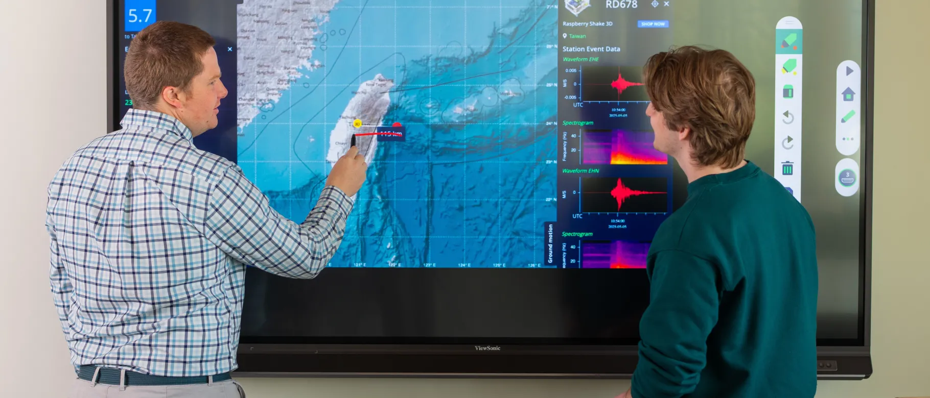 UNE Professor Will Kochtitzky displays a seismic activity map with a student