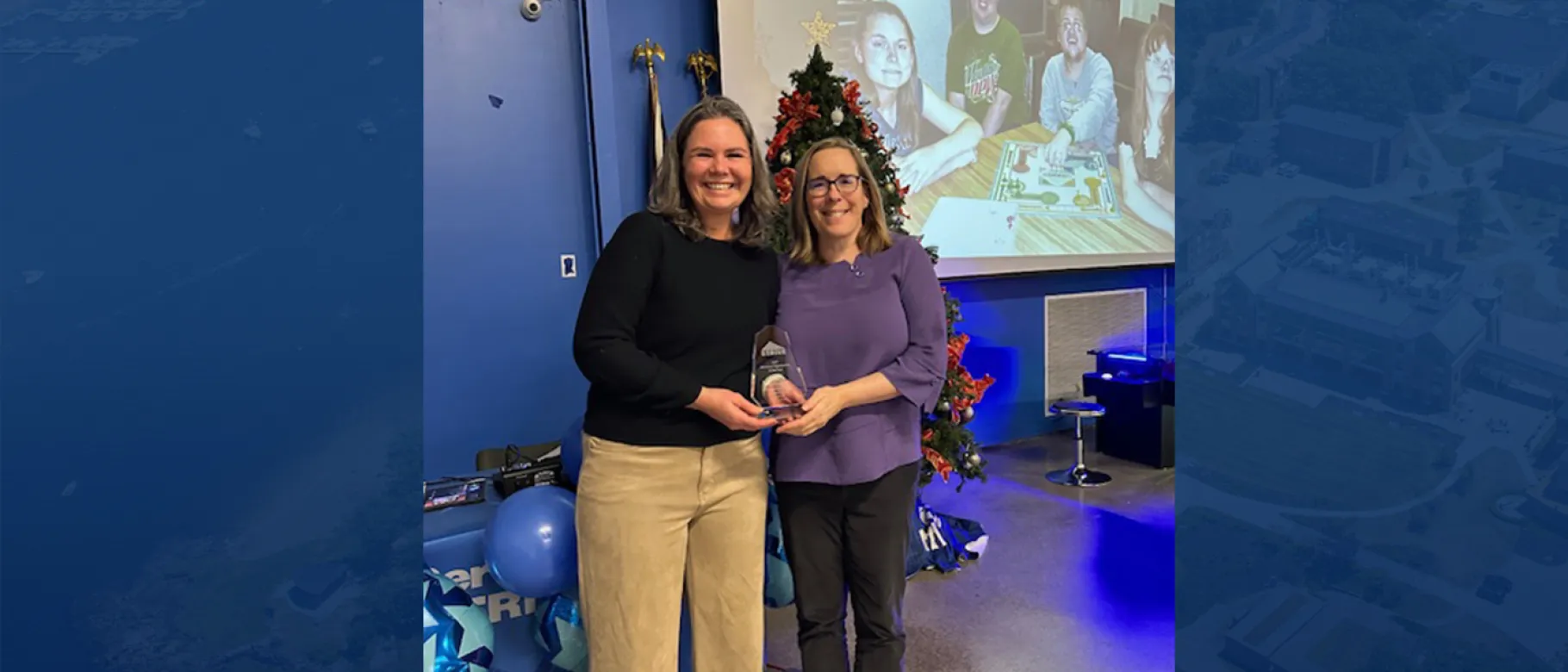 Two UNE faculty members (Jessica Walton and Erin McCall) pose with an award trophy