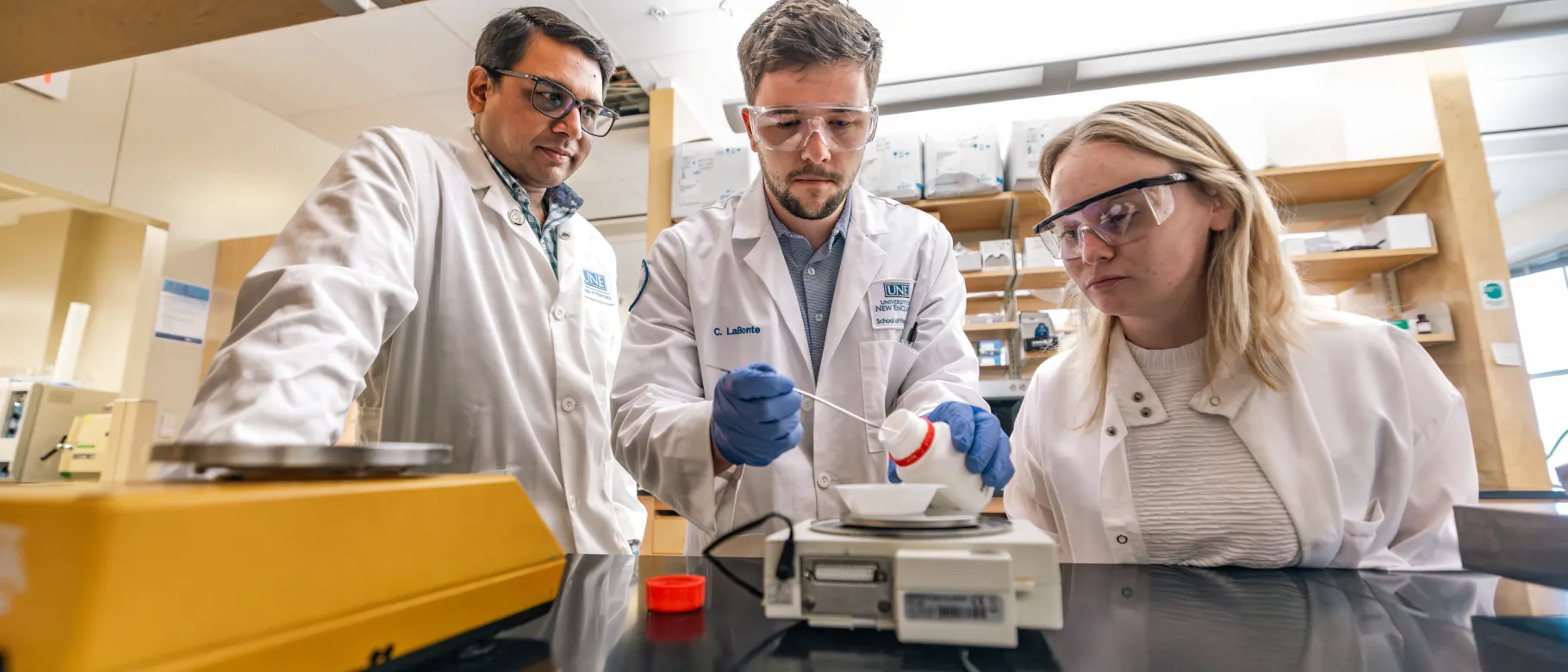 A UNE researcher and students work in a Portland Campus lab