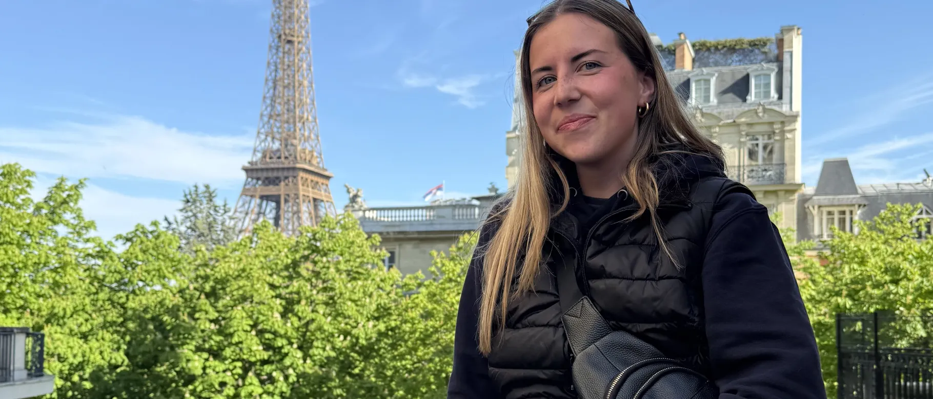UNE student Cally Gudroe poses in Paris with the Eiffel Tower in the background