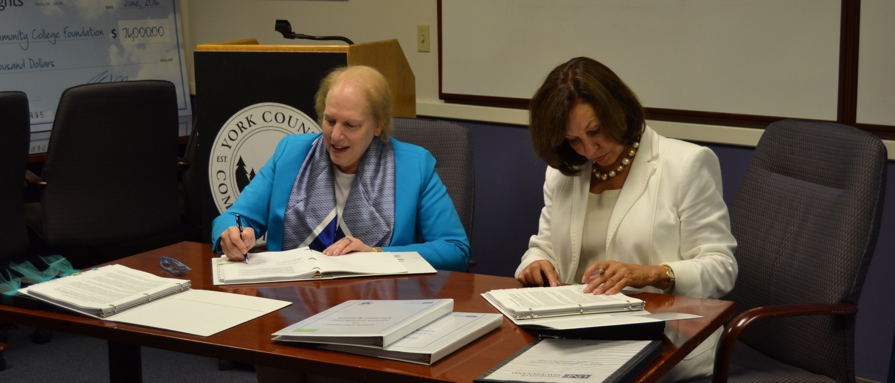 President of YCCC Barbara Finkelstein (left) and UNE President Danielle Ripich sign the transfer agreement.