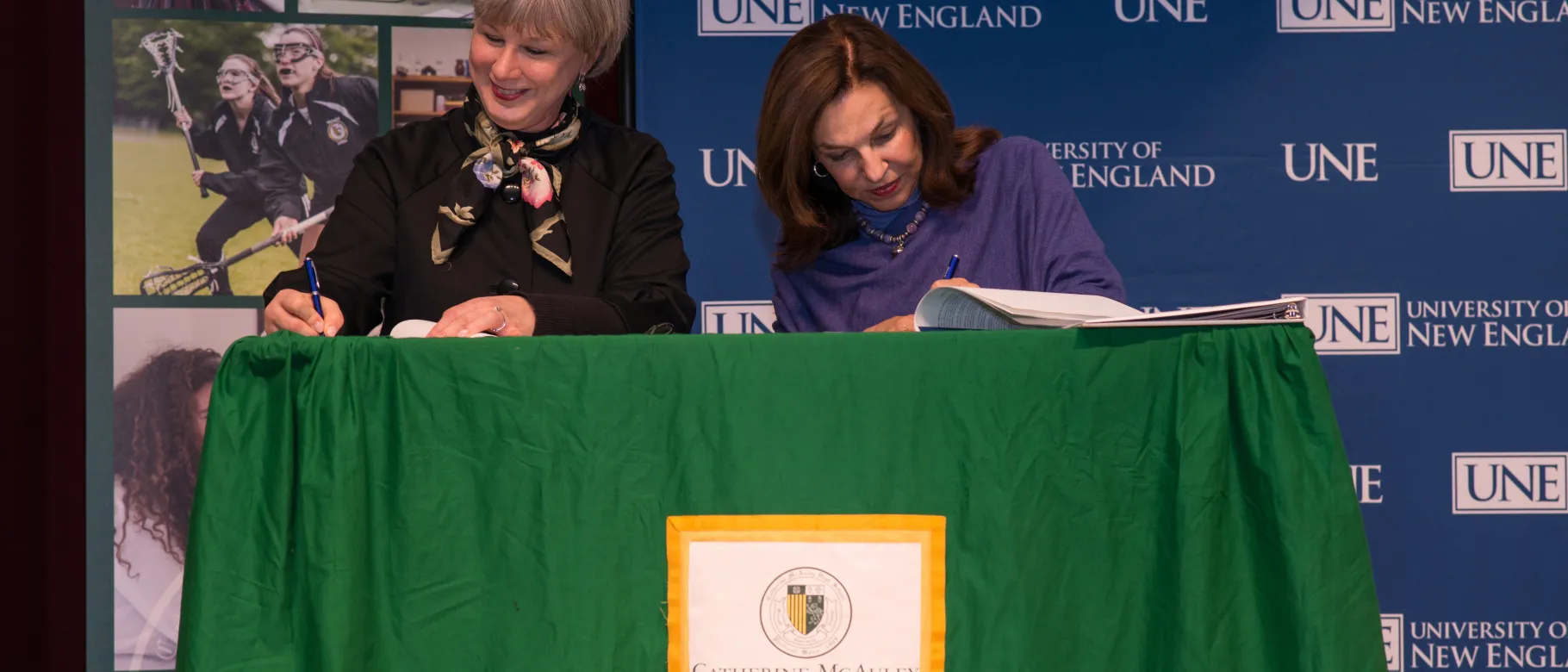 Catherine McAuley's Head of School Kathryn Woodson Barr and UNE President Danielle Ripich officialize the new agreement between 