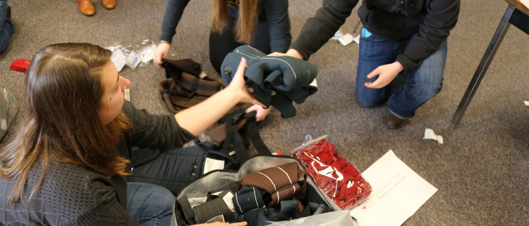 Medical students Allison Hockman and Tess Strand pack baby carriers with freshman Marissa Laramie