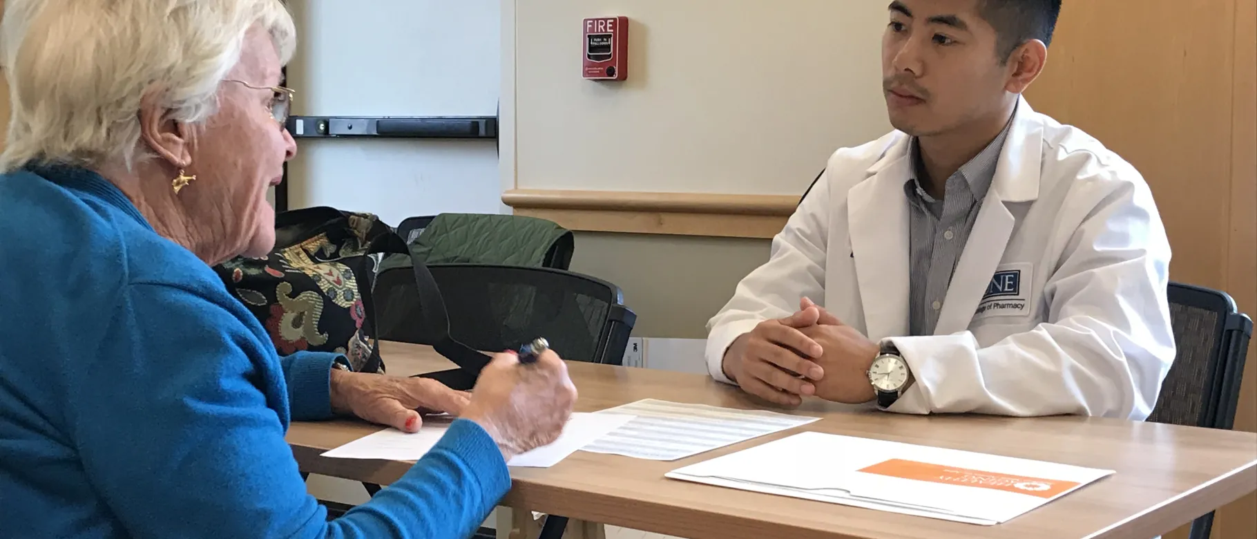 College of Pharmacy student Brian Lui chats with clinic attendee Jane Gleason about her medication