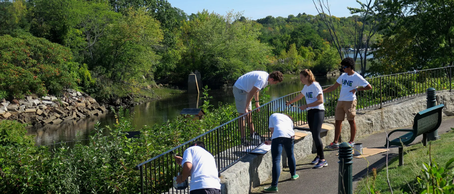 UNE volunteers paint the fence at Mechanics Park in Biddeford as part of UNE's Day of Service.