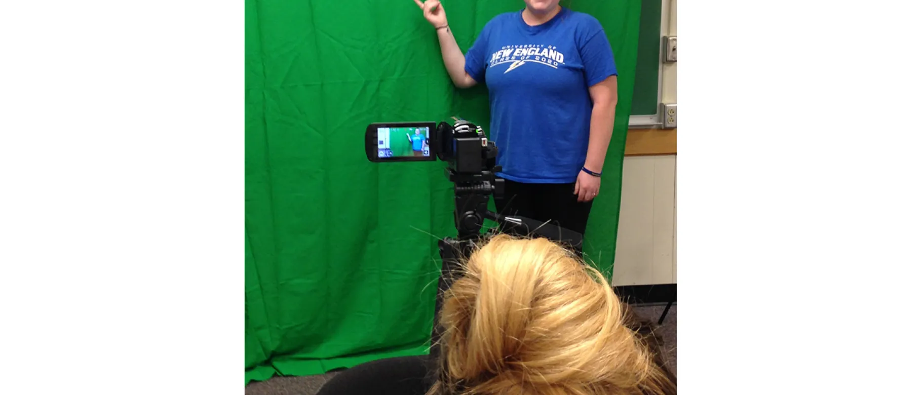 Lindzee Ridley, digital literacy adviser and second-year Athletic Training major, demonstrates use of the green screen as Megan