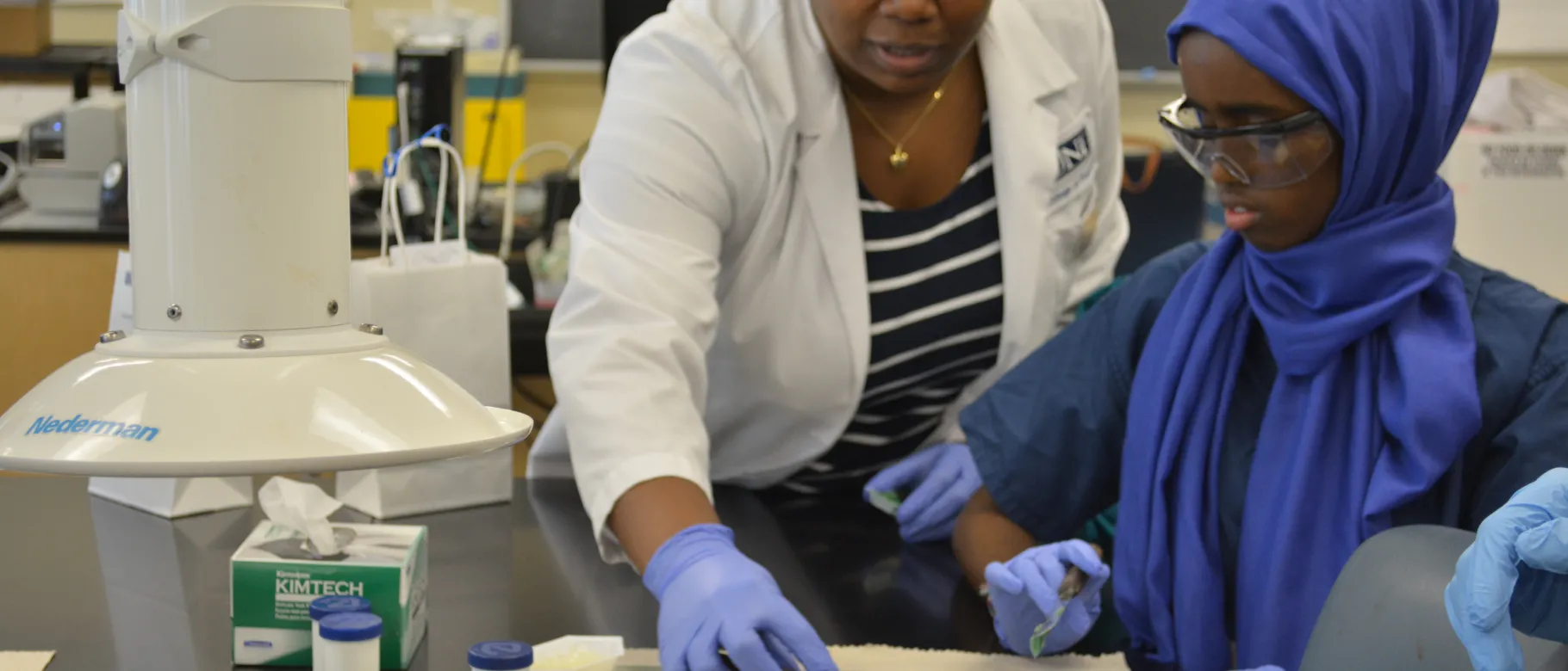 UNE pharmacy student shows a Lewiston High School student how a pharmaceutical dental compound would be made.