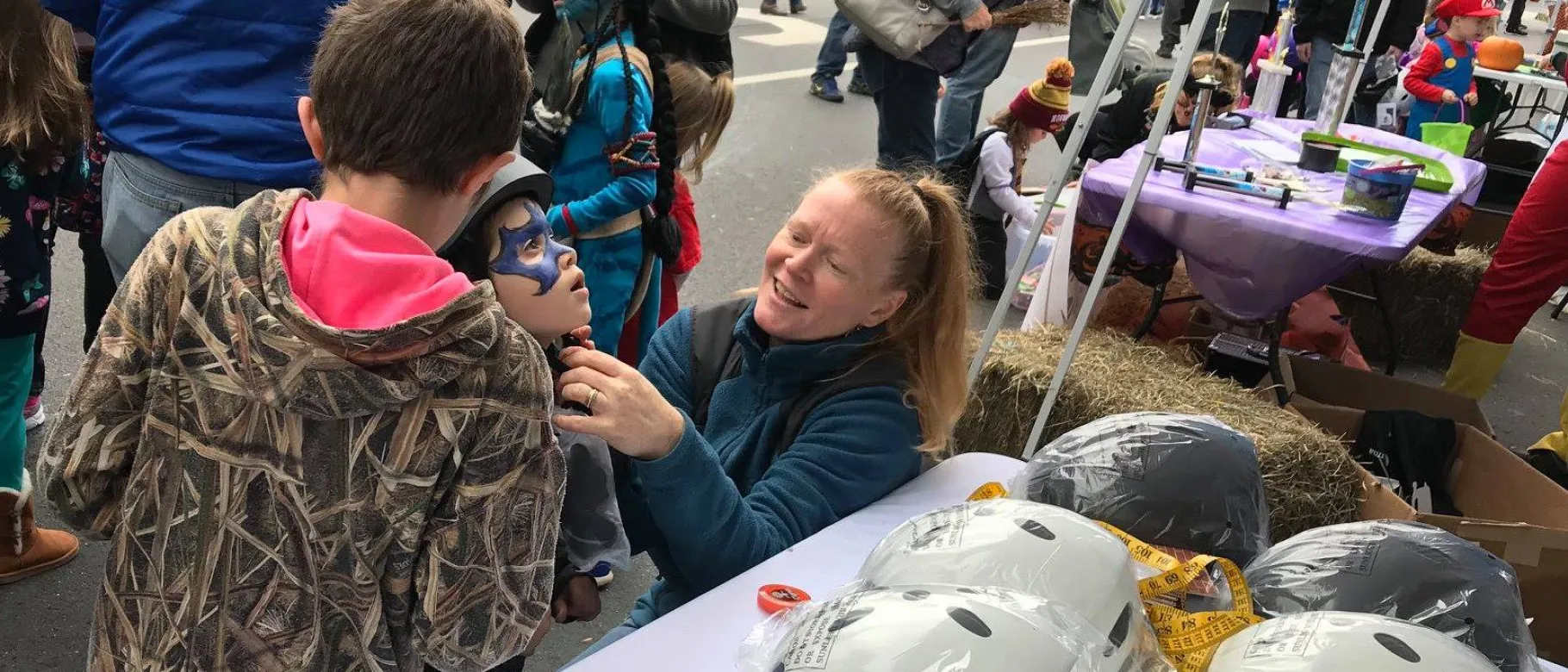UNE graduate student Julie Moulton adjusts a helmet at the annual Saco Pumpkin Harvest Festival