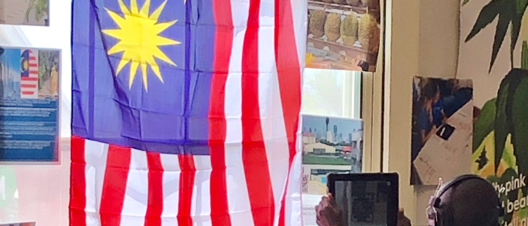 A student in Portland sits under the flag of Malaysia as he learns about a child from that country