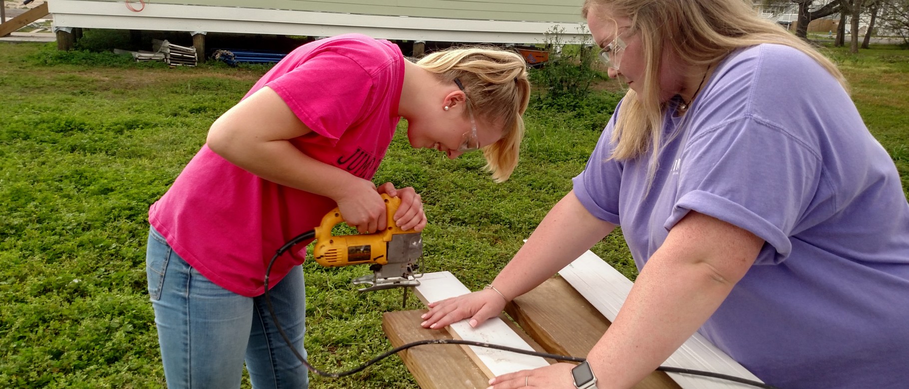 UNE students Sammi Clough and Meghan Aiello do some trimming on wood for a house being built by volunteers