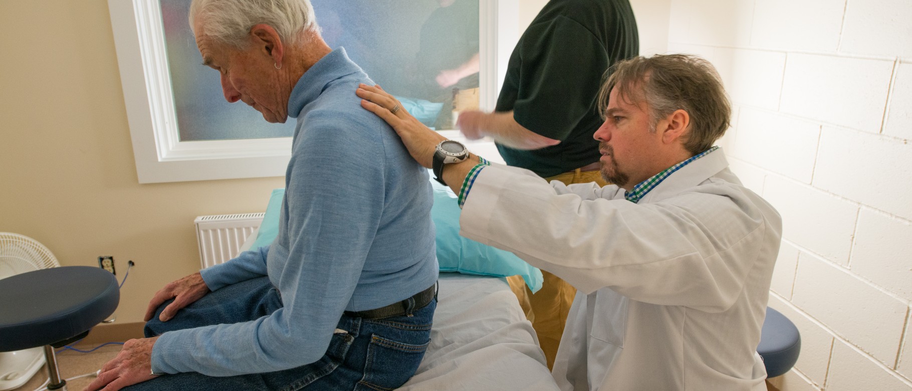 John Cooper (UNE COM, ’18) and Stuart Damon, D.O., treat a patient at a clinic in Vinalhaven 