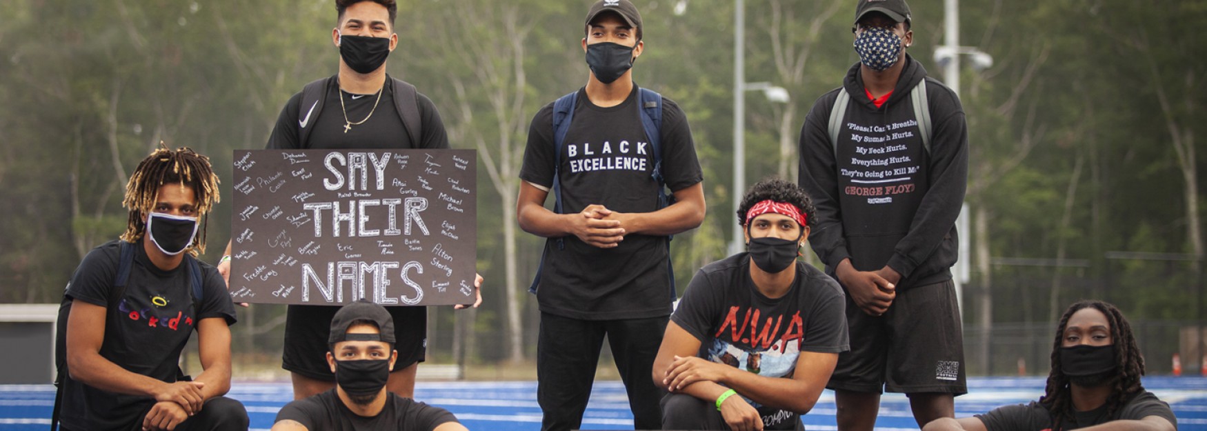 Members of the U N E football team wear black clothing and pose for a photo at the Black Lives Matter march on the Biddeford campus