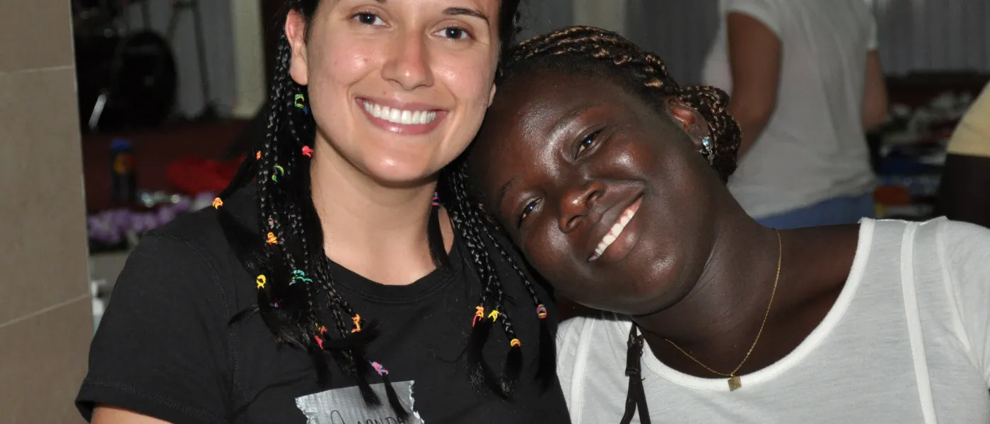 A U N E clinician with braided hair like her smiling Ghanaian patient's