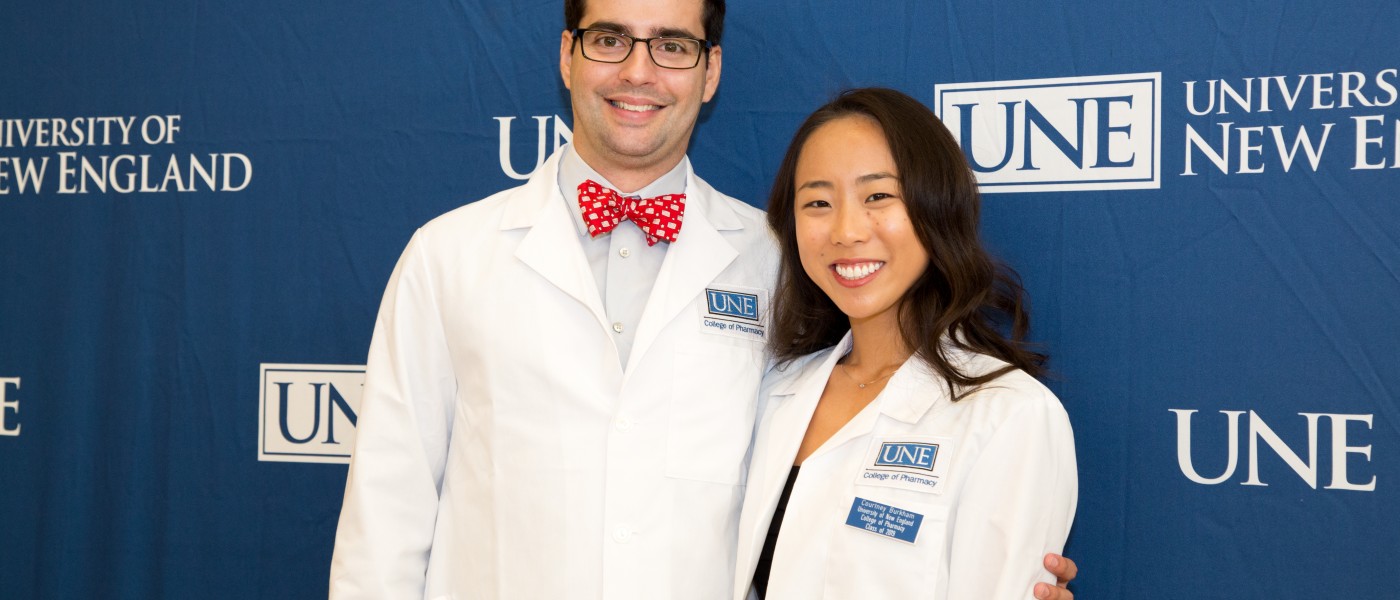U N E College of Pharmacy students in front of UNE banner after White Coat Ceremony