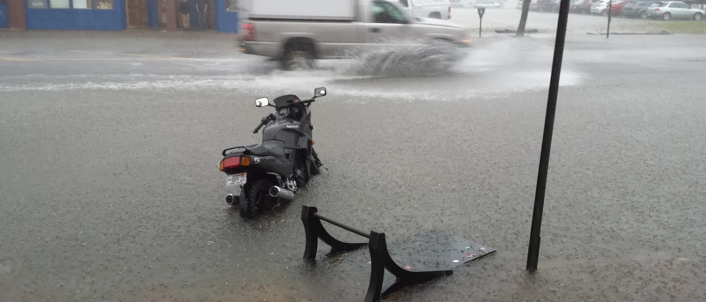 A motorcycle sits almost covered by water in a flooded street
