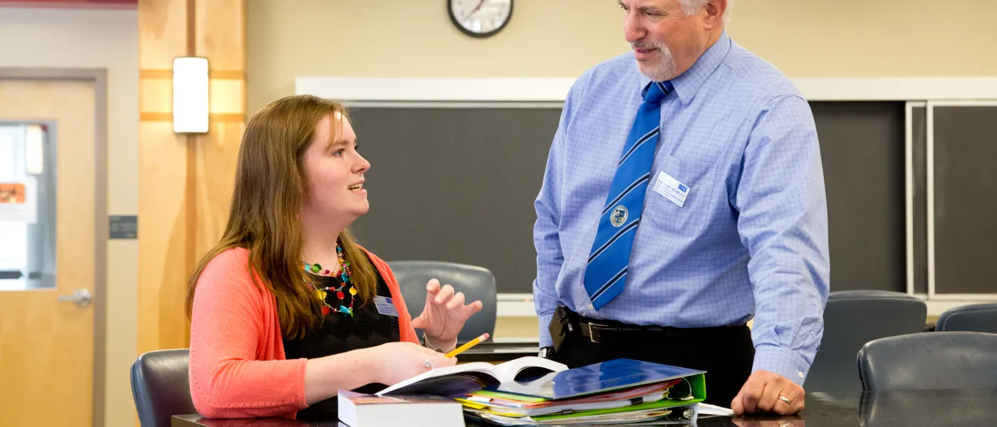 U N E College of Pharmacy student studies in a classroom with professor