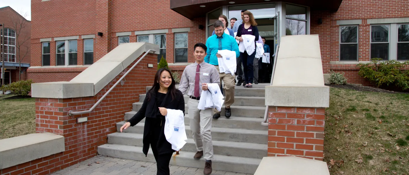 U N E College of Pharmacy students walk out of building with white coats