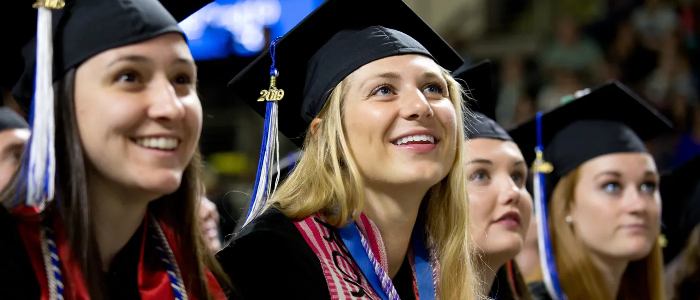 Four female students watch the commencement ceremony