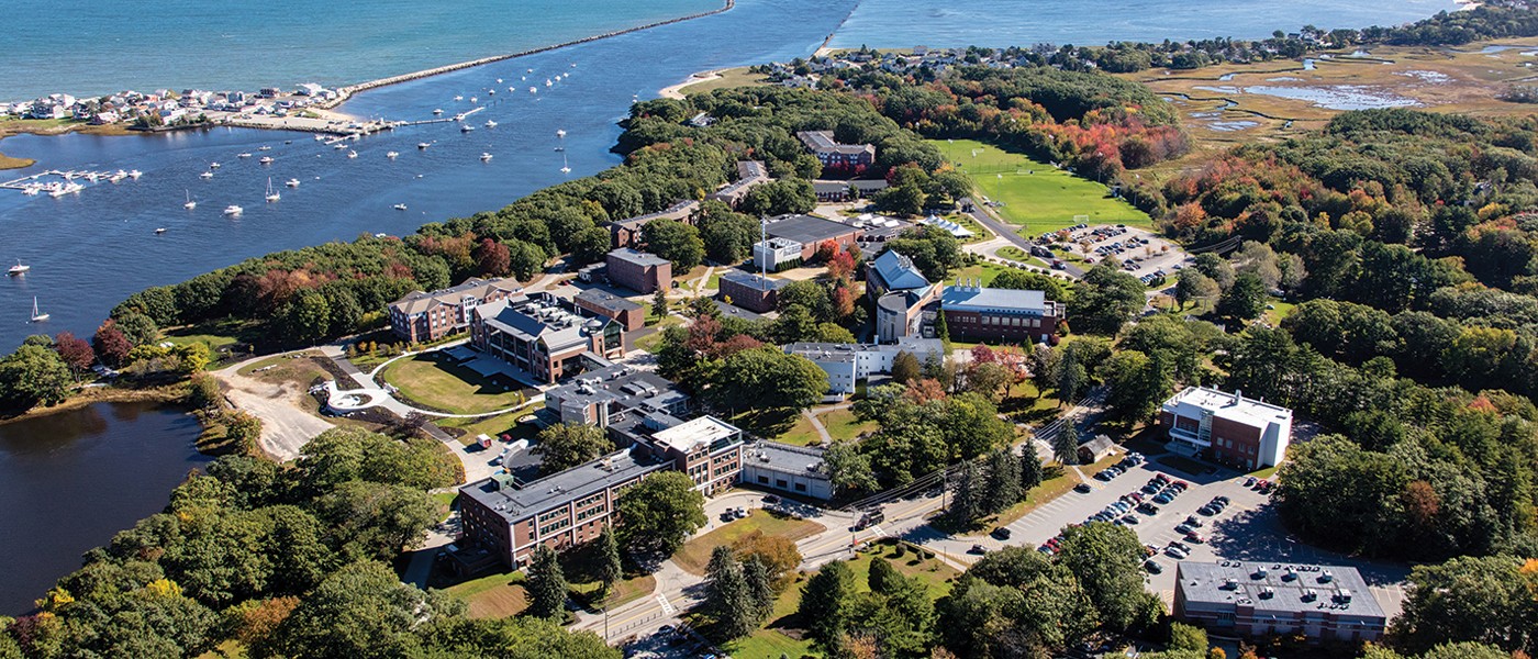 An aerial photograph of U N E's biddeford campus including buildings and the ocean