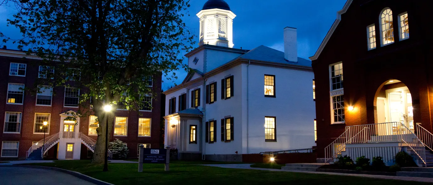exterior of three buildings at night on the u n e portland campus