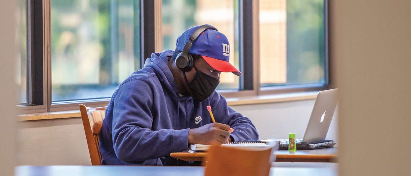 student wearing mask studying on campus