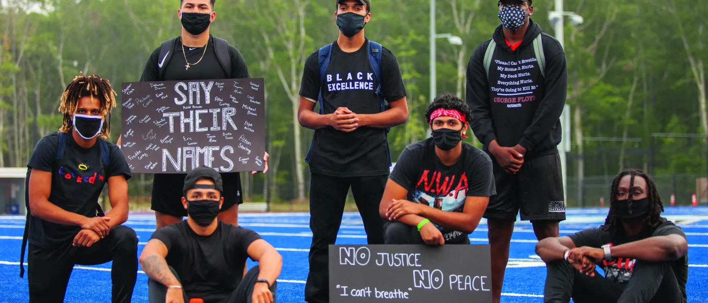 members of u n e's football team who organized the march for social justice pose with signs