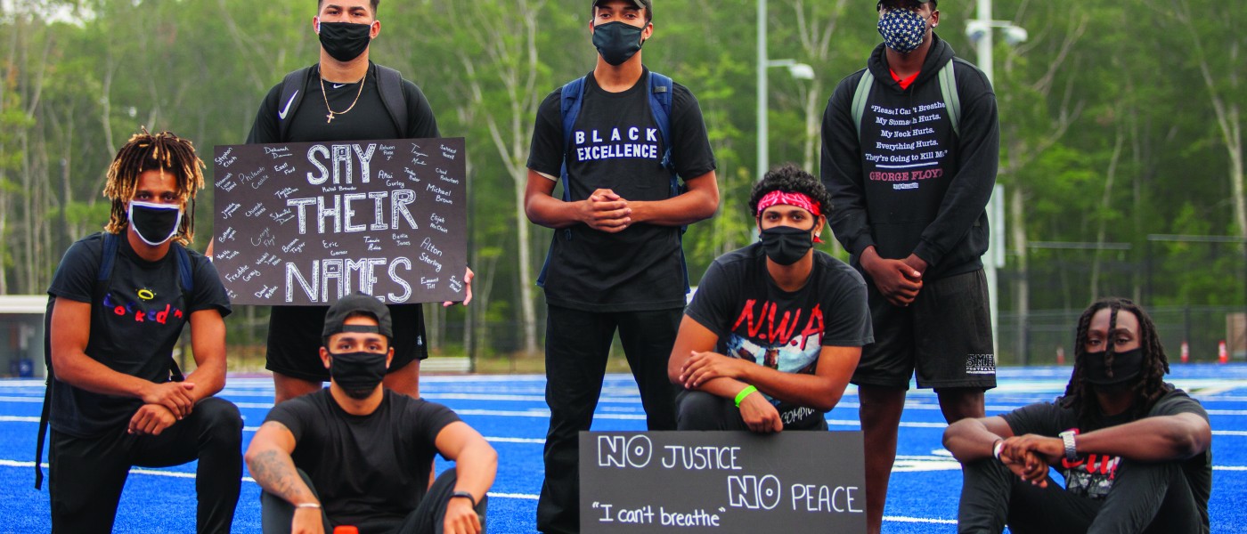 members of u n e's football team who organized the march for social justice pose with signs 