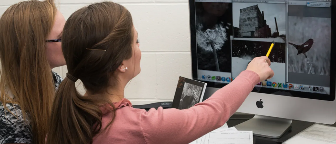 Two U N E liberal arts students examine images on a computer