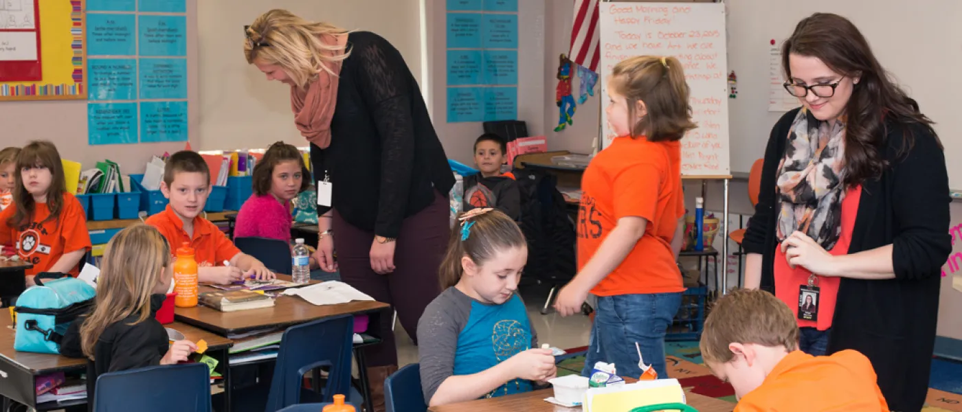 Two U N E liberal arts students work in a classroom with elementary school students