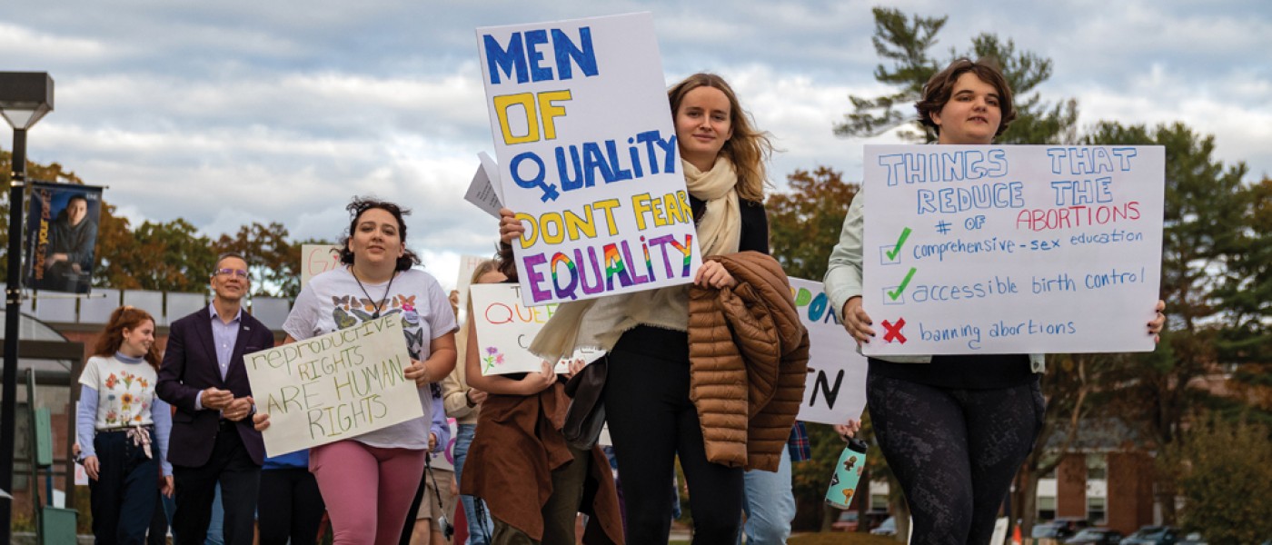 U N E students holding posters and walking during the Women's March